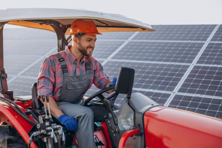 rolnik w traktorze obok paneli fotowoltaicznych